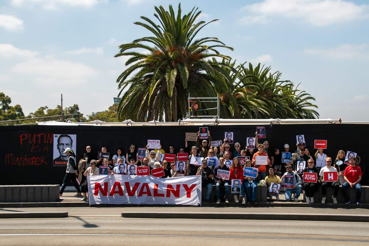 A group of demonstrators holding placards and a banner that show messages in support of Russian opposition figure Alexei Navalny.
