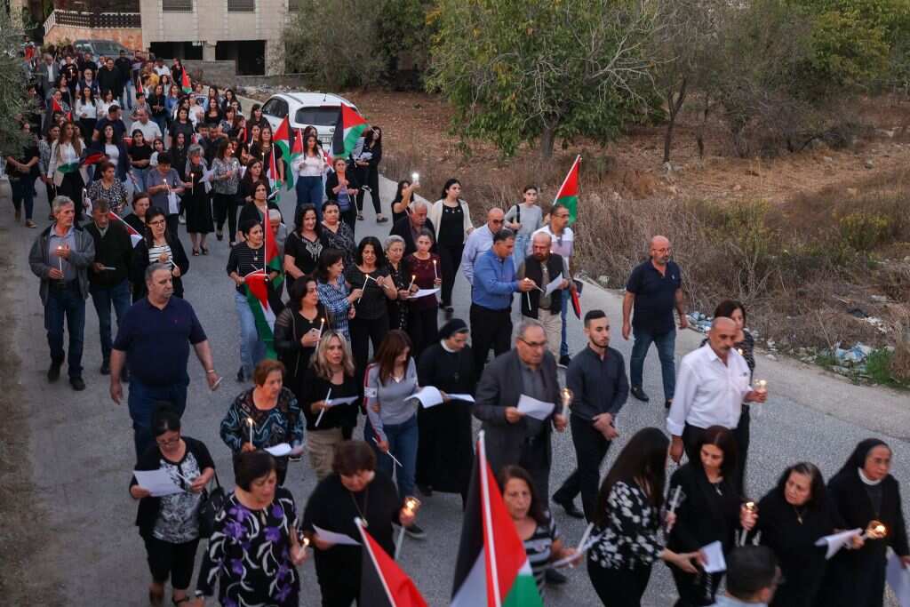 People carrying Palestinian flags wander along a country road.