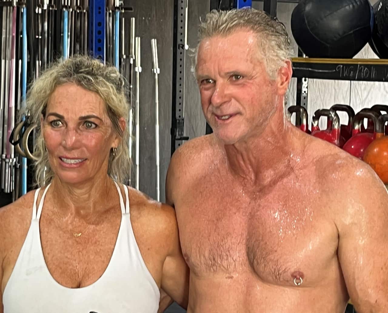 A woman in a white top stands next to a man with a bare chest.