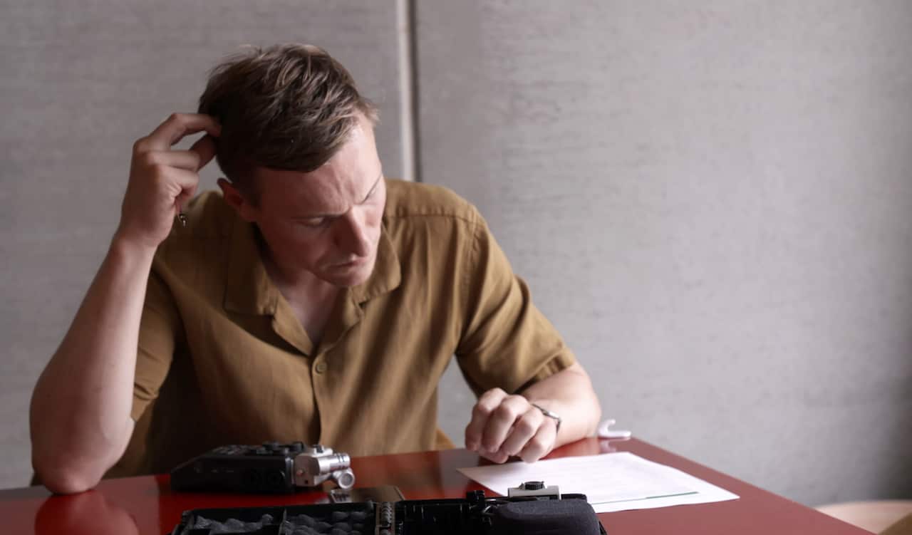 A man looks down at papers on the desk in front of him.jpg