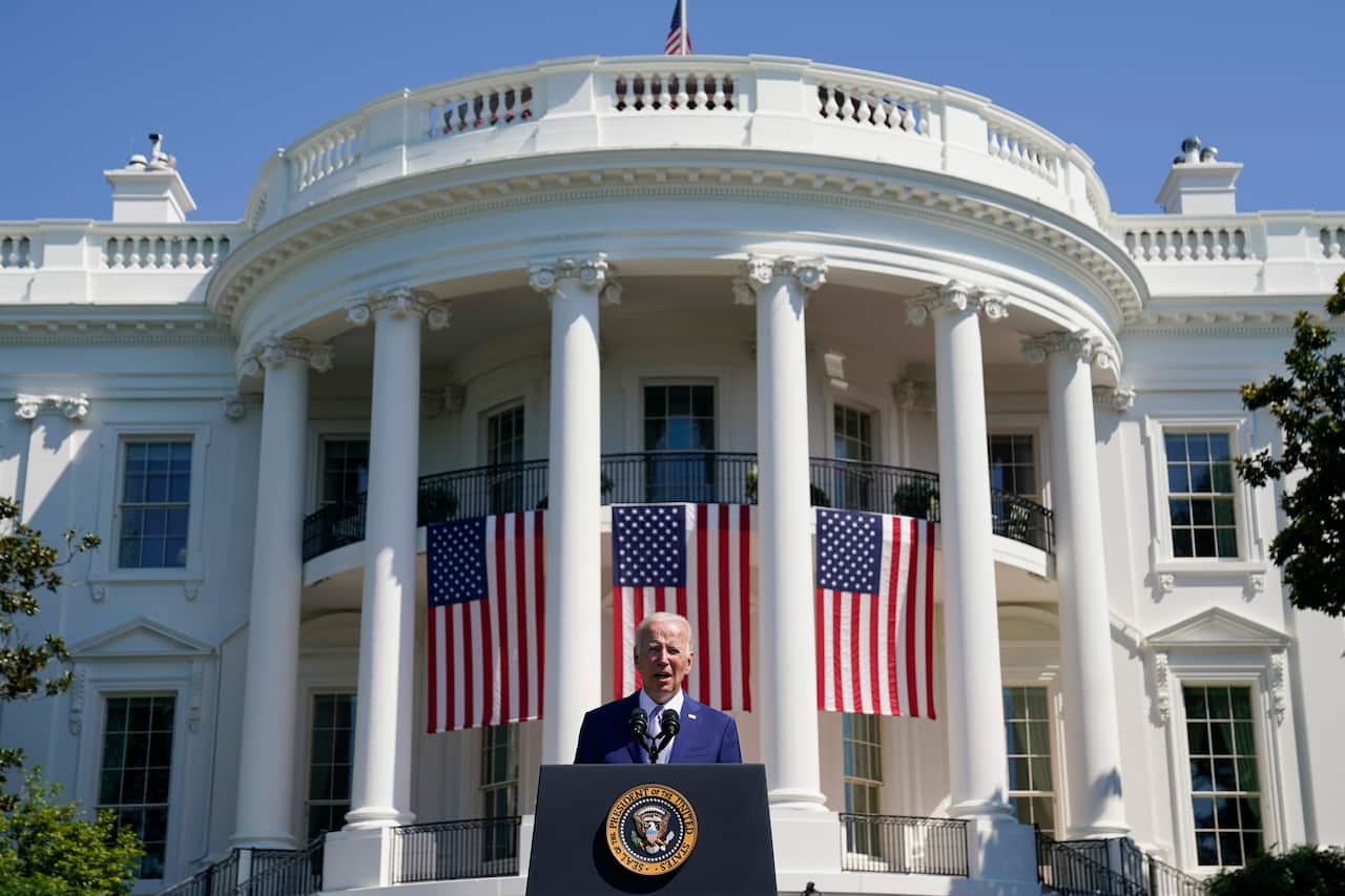 Joe Biden standing at a lectern on a lawn outside the White House.