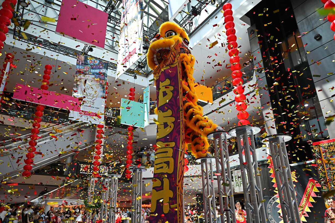 Confetti falls from the ceiling of a shopping center as people celebrate.