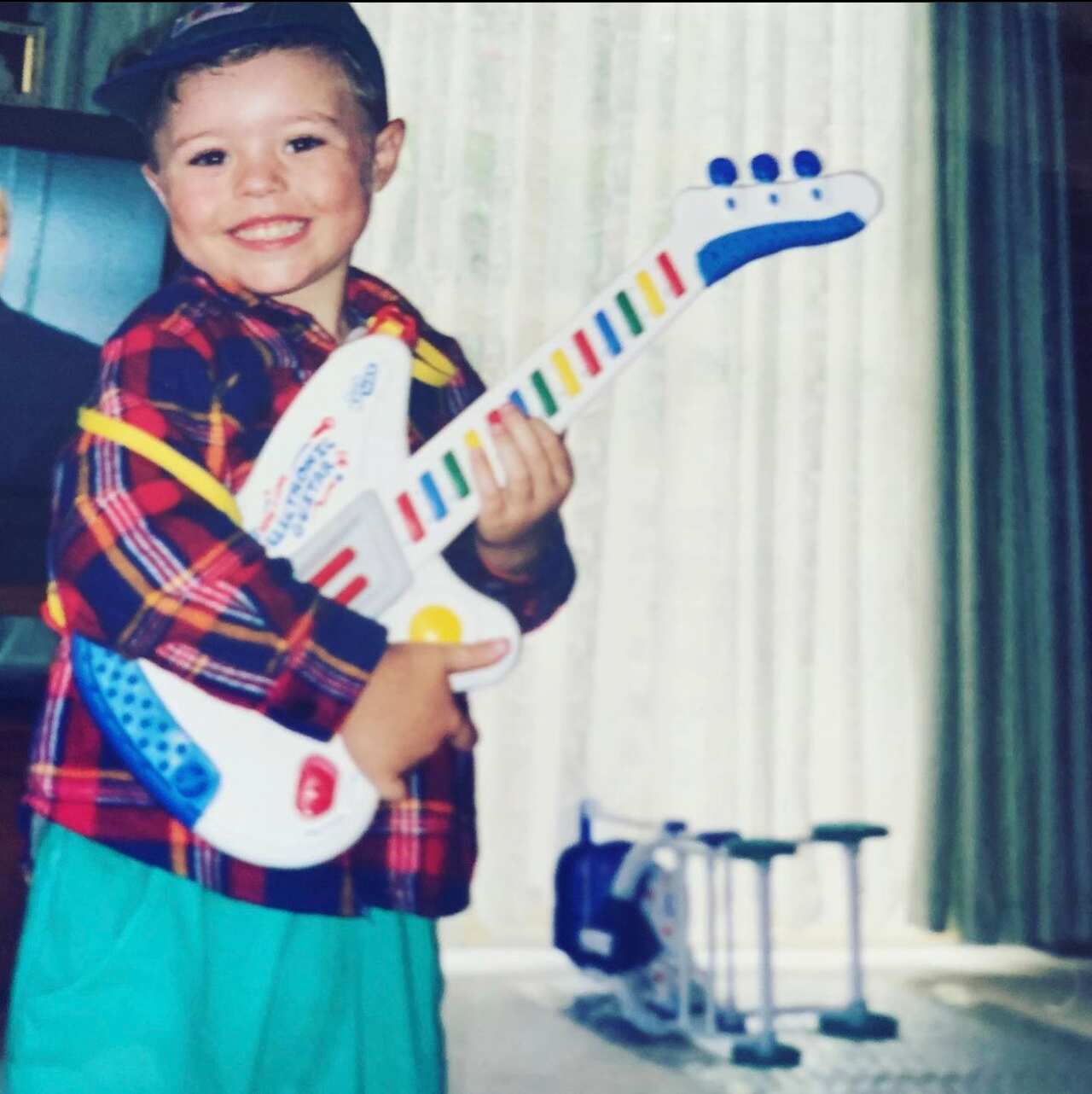 A toddler holding a toy guitar