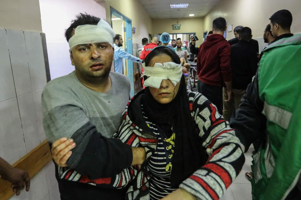 A man leading an injured woman in a hospital corridor