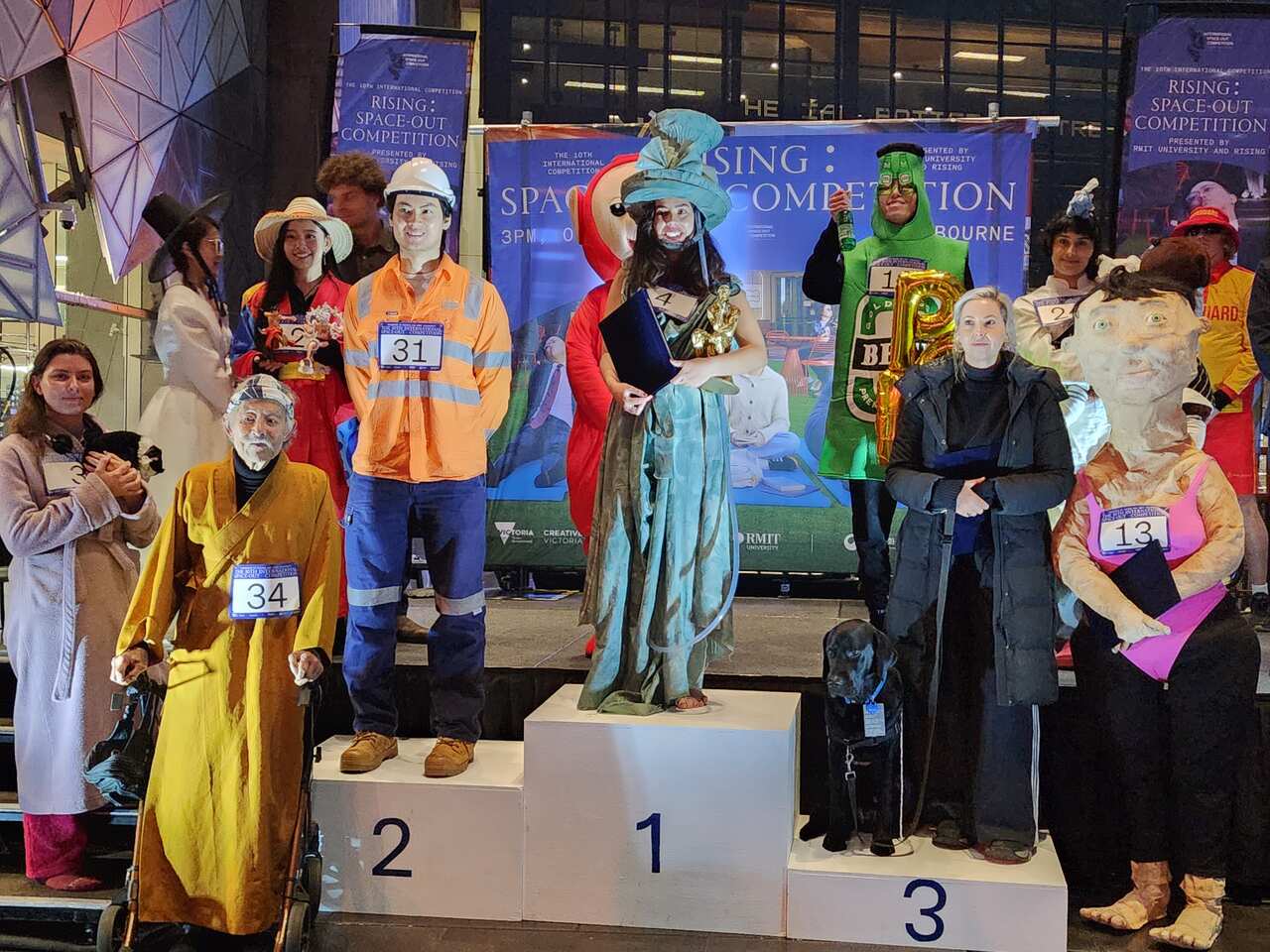 Ten people wearing costumes stand on and around a podium.