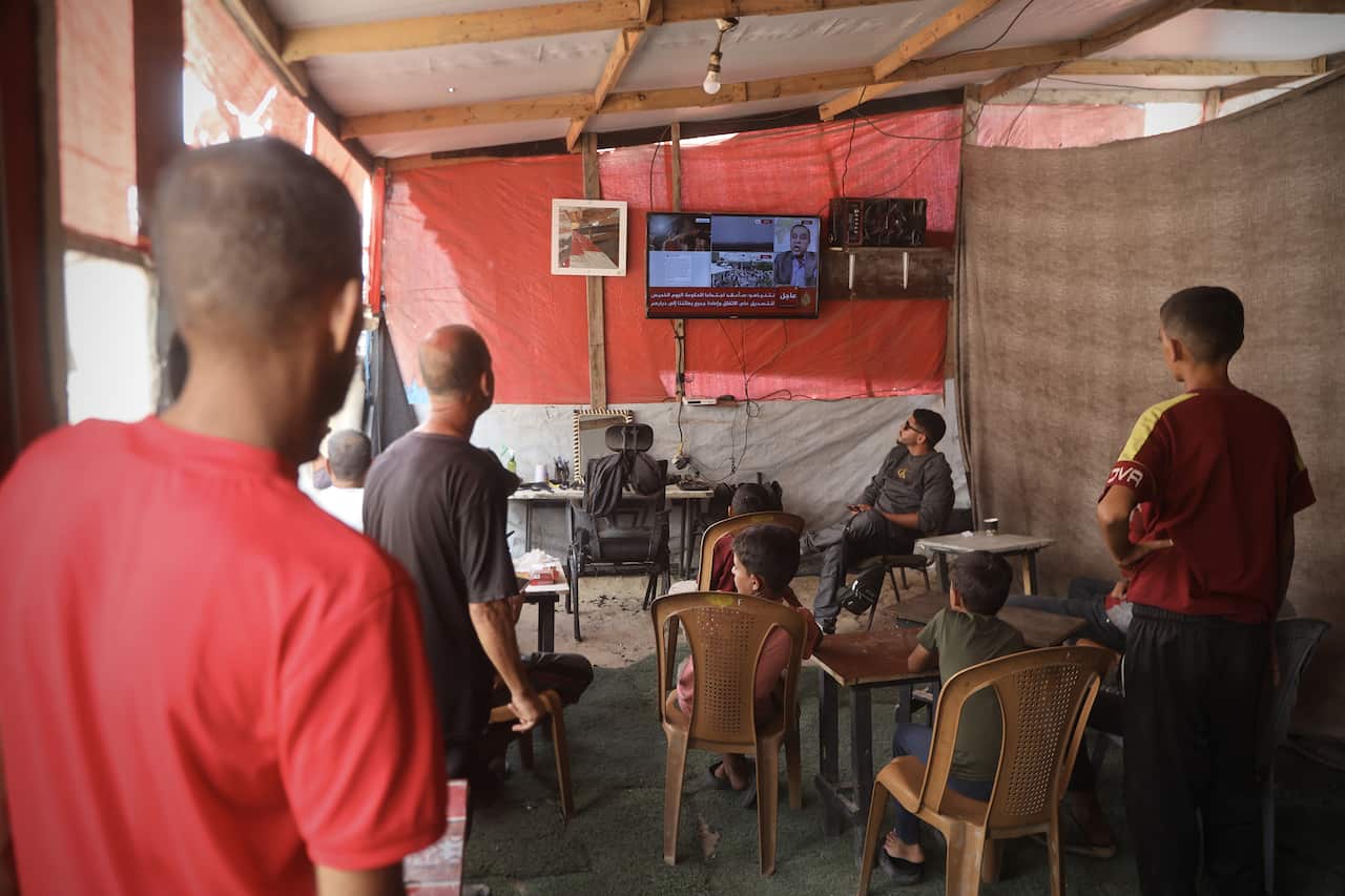 Gazans watch a television which is broadcasting news of the ceasefire agreement.