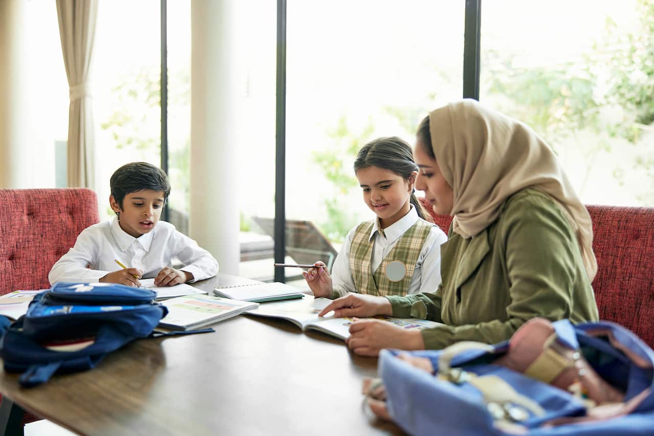 Saudi school children doing homework with their mother