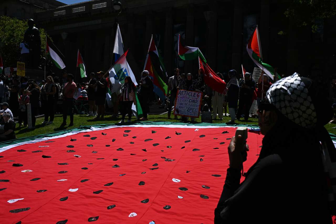 A crowd unfurls a lare watermelon flag