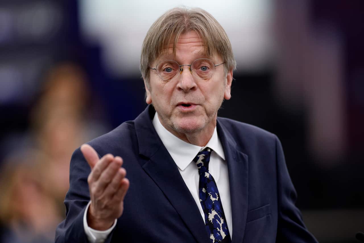 A man wearing a suit, tie and glasses is speaking.