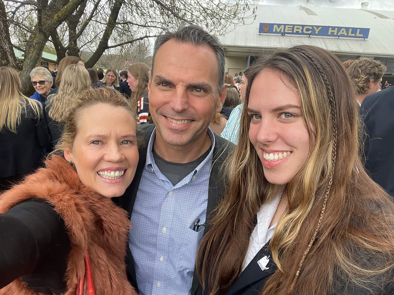 A man with two women eithe side of him, all smiling and posing for a selfie