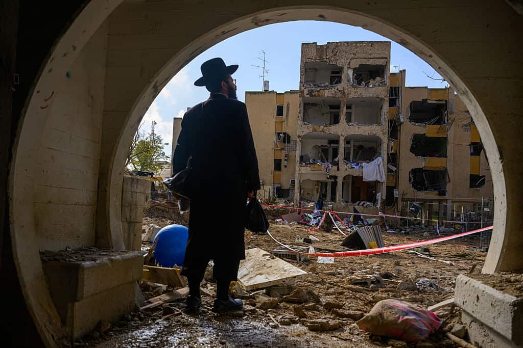 A man looks out at the destruction after an Iranian ballistic missile strike destroys multiple residential buildings.