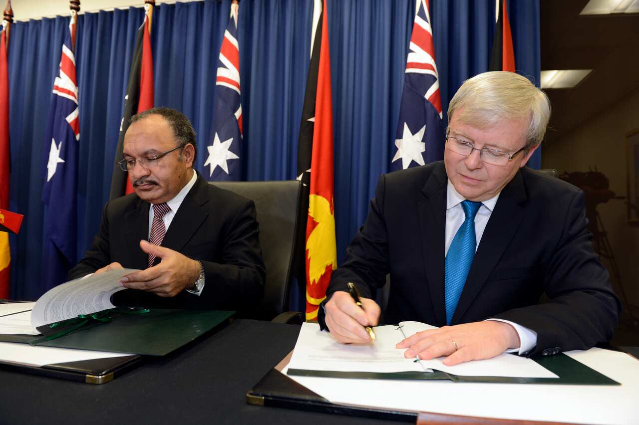 Peter O'Neill (left) and Kevin Rudd (right) sitting at a desk with documents in front of them