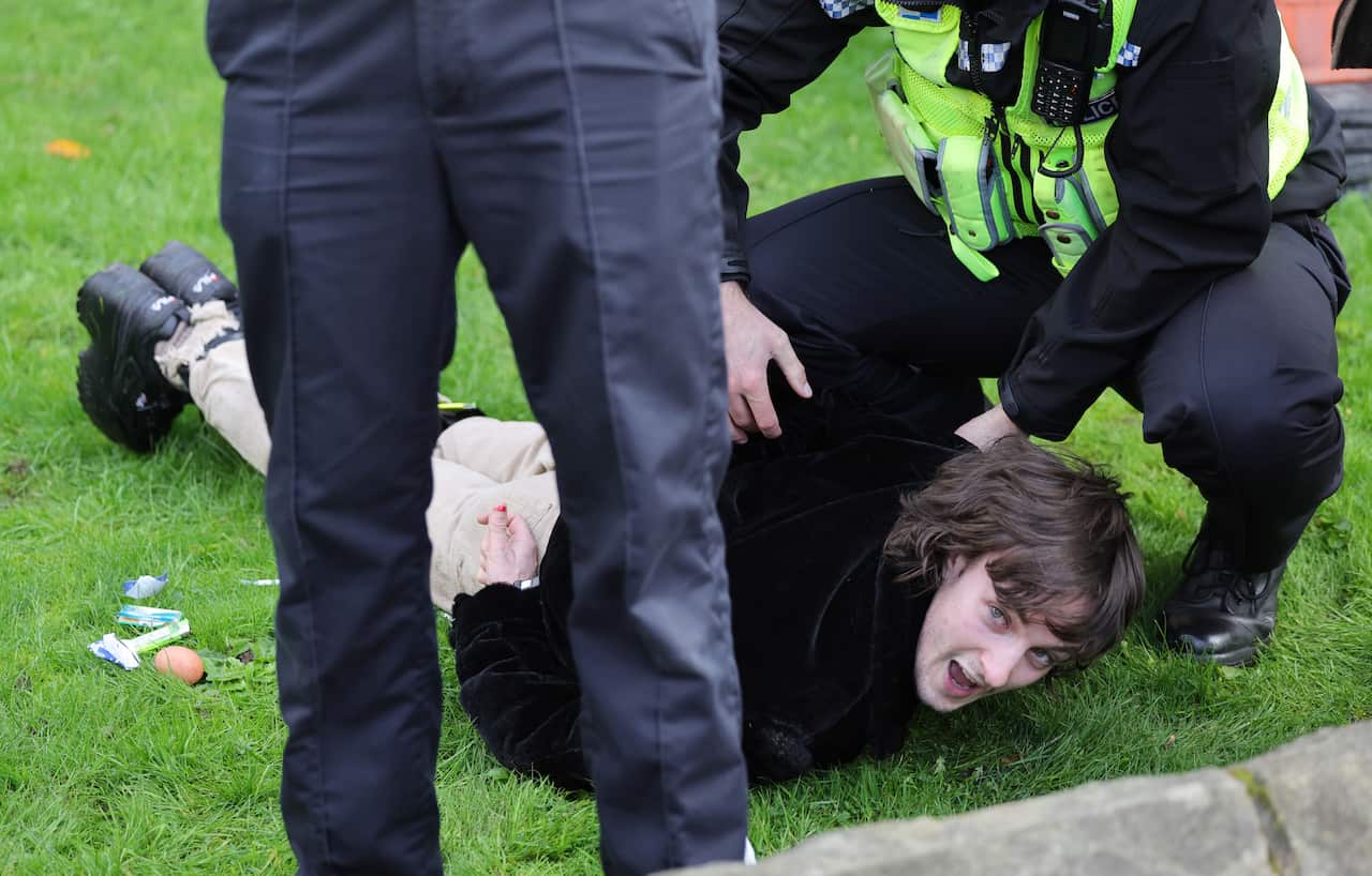 Police arrest a man who is on the ground.