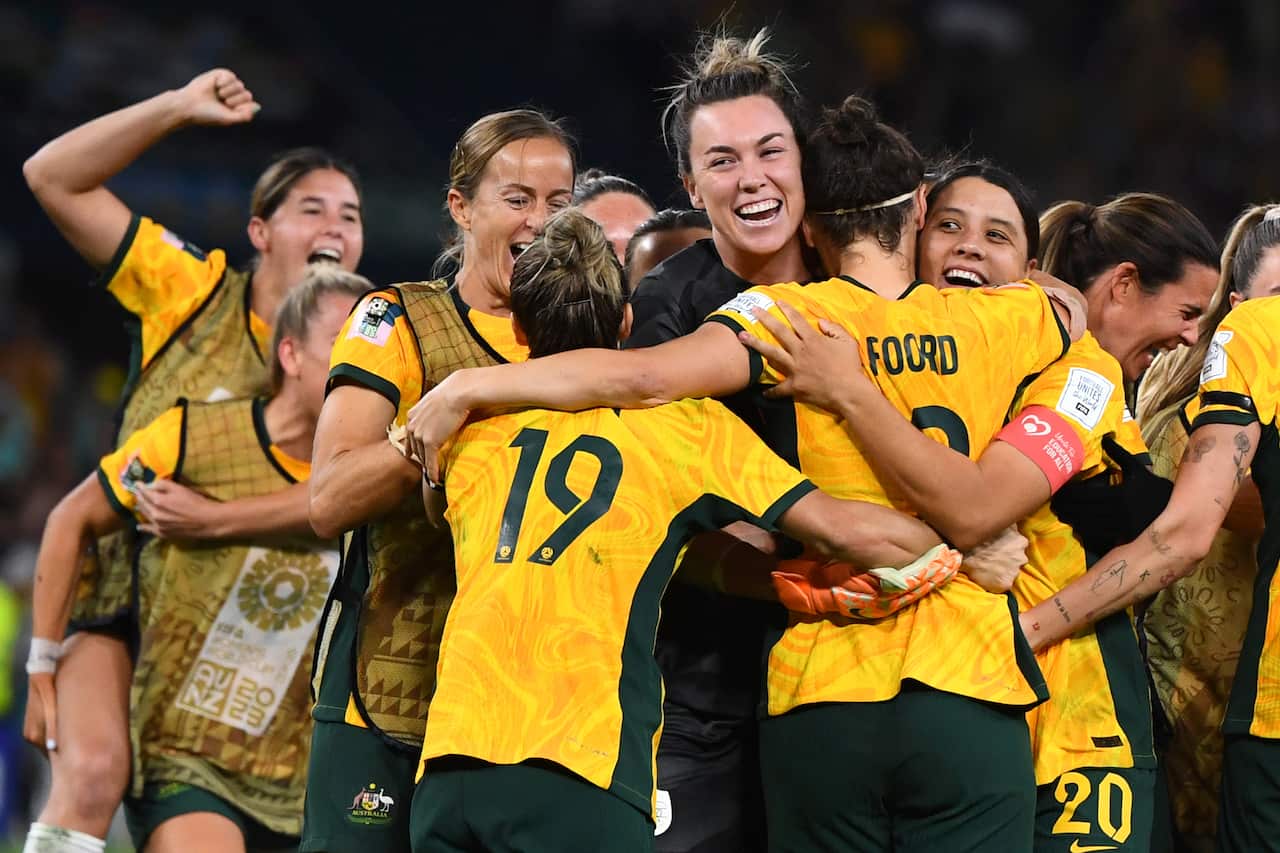 Matildas players huddling and cheering.