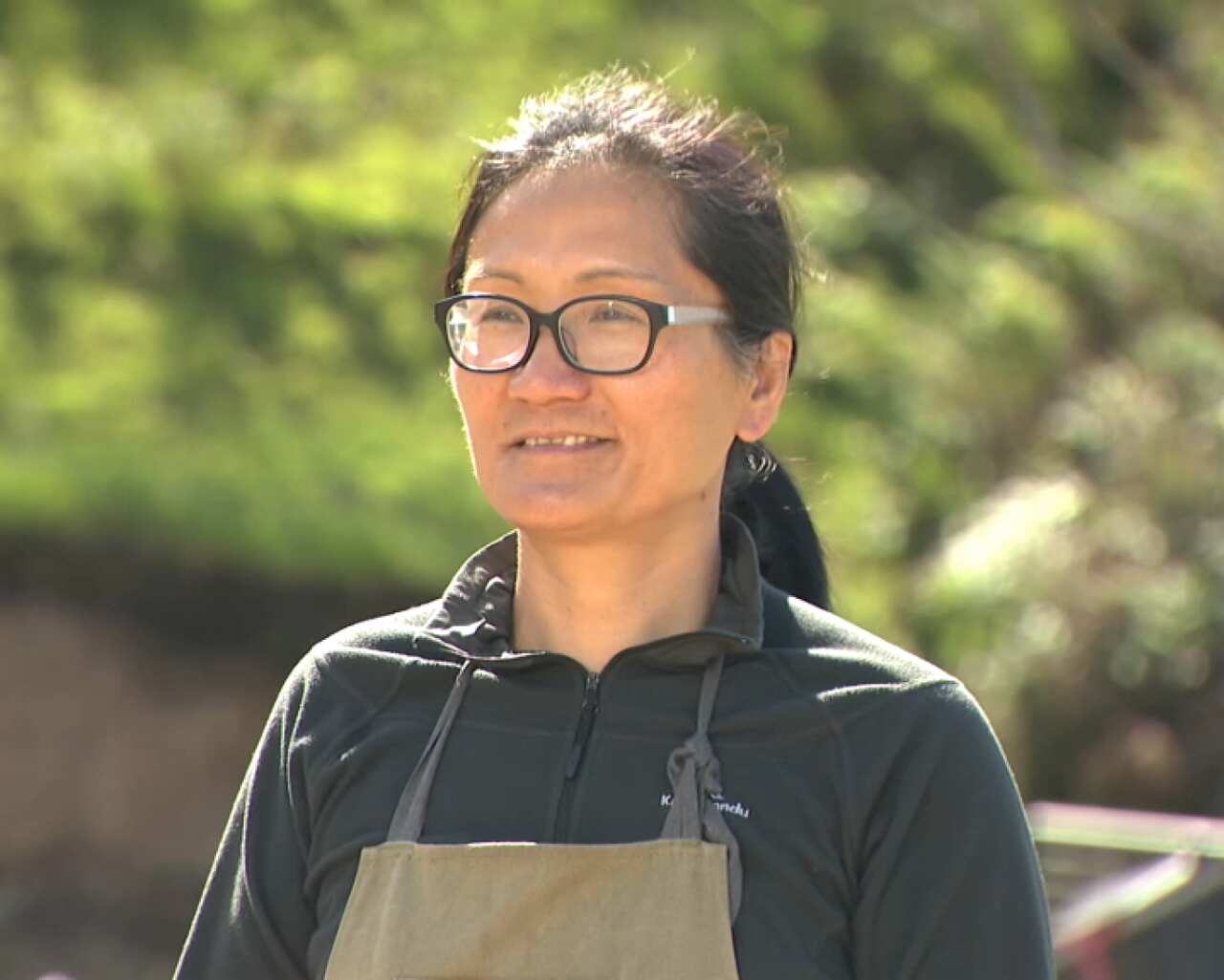 A woman in overalls stands in a field.