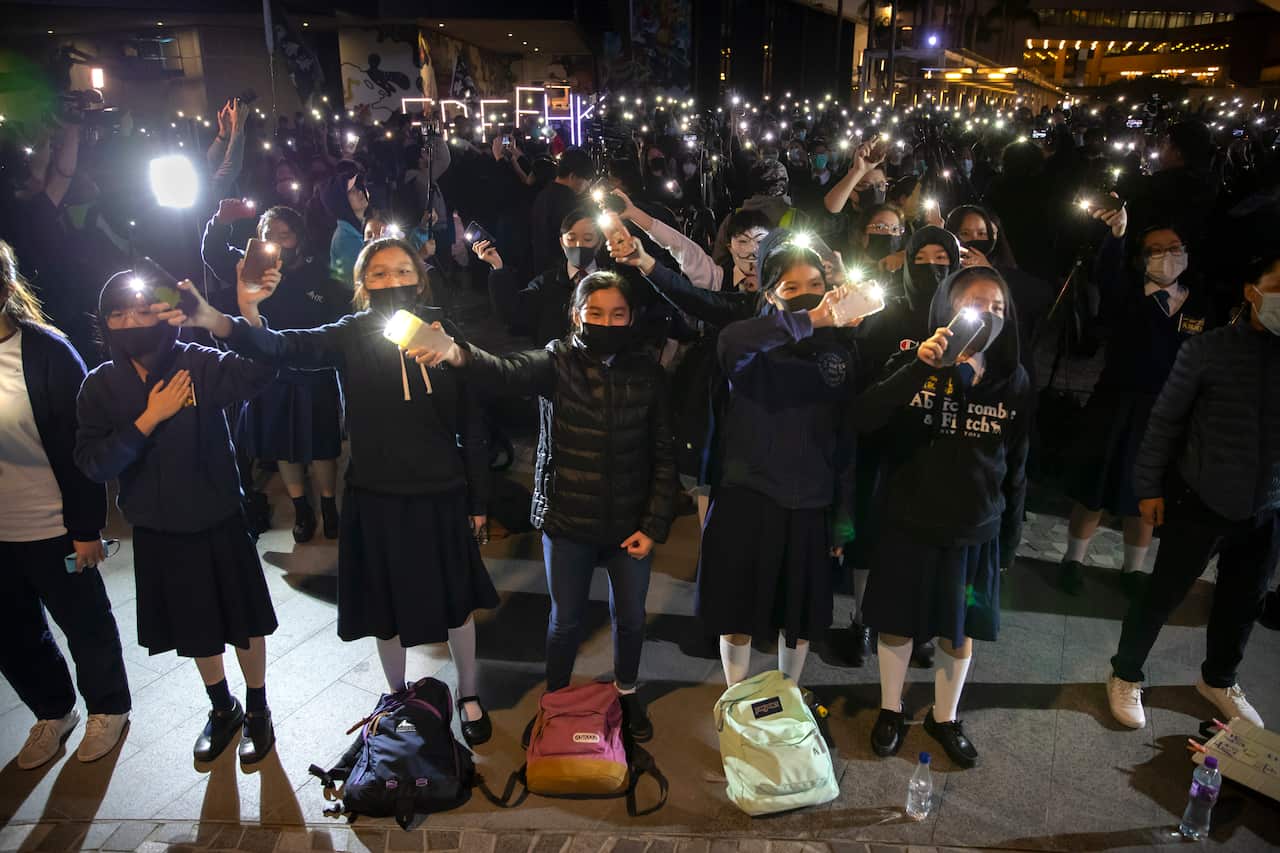 Protesters wave their smartphones in a street while singing 