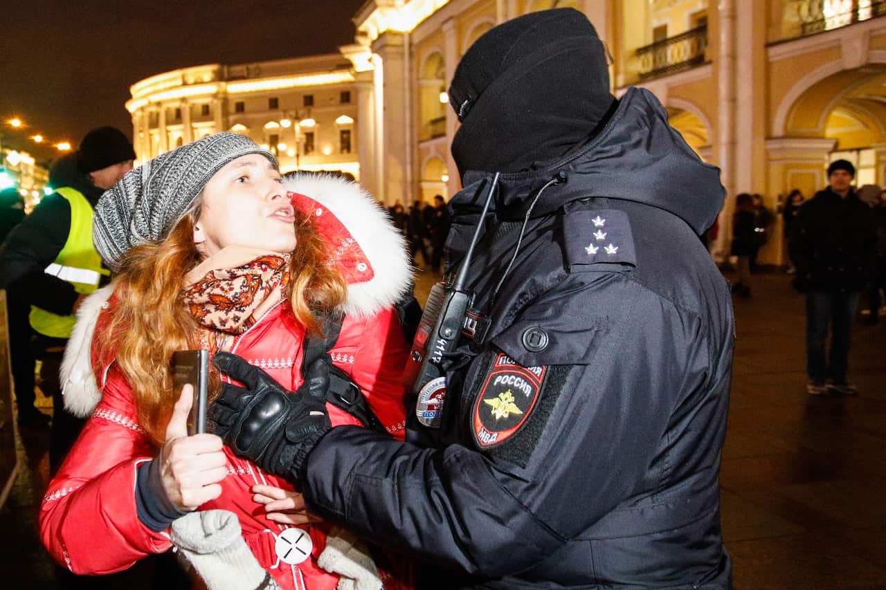 A law enforcement officer approaches a woman outside the Gostiny Dvor business centre in Moscow during an unsanctioned protest against the military operation in Ukraine.