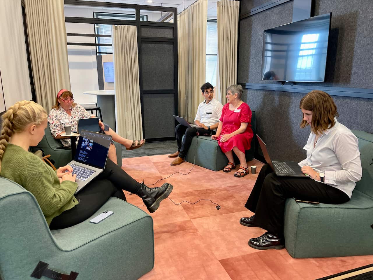 People sit on couches with their laptops. 