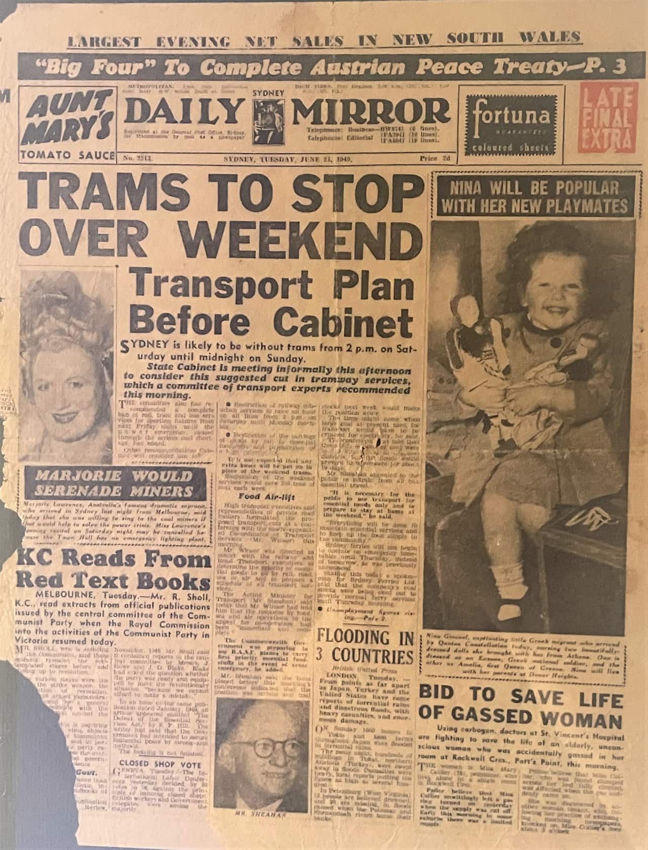 An old newspaper with the photo of a young girl holding small dolls.