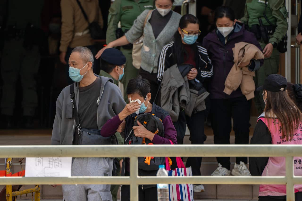 A woman covering her face with a tissues paper after leaving a community center where they view photos of deceased victims to identify them as a major fire engulfs several residential buildings at Wang Fuk Court on November 28, 2025 in Hong Kong