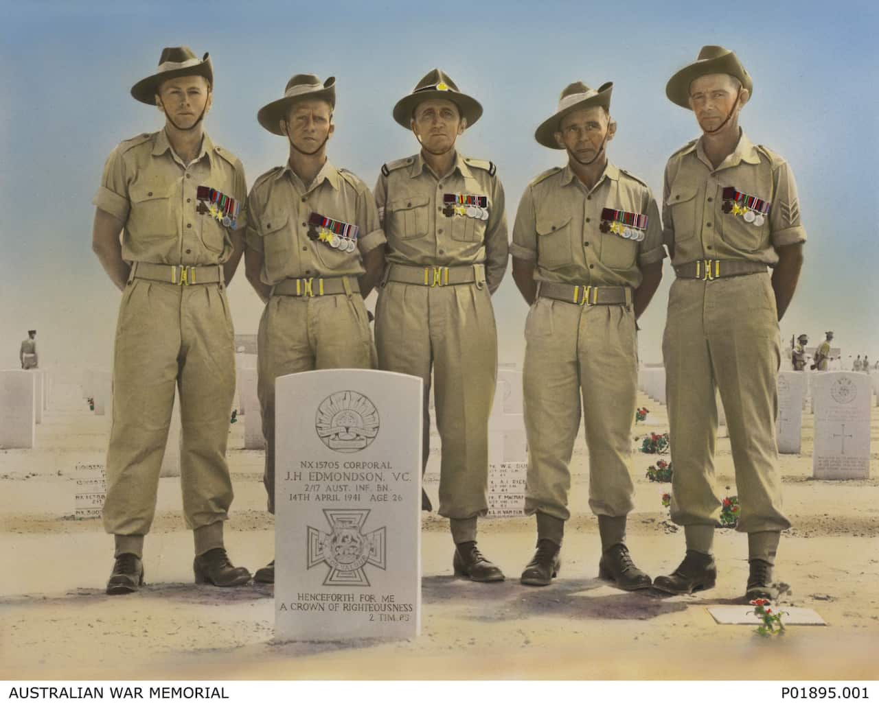 Five men in old army uniforms standing behind a gravestone.