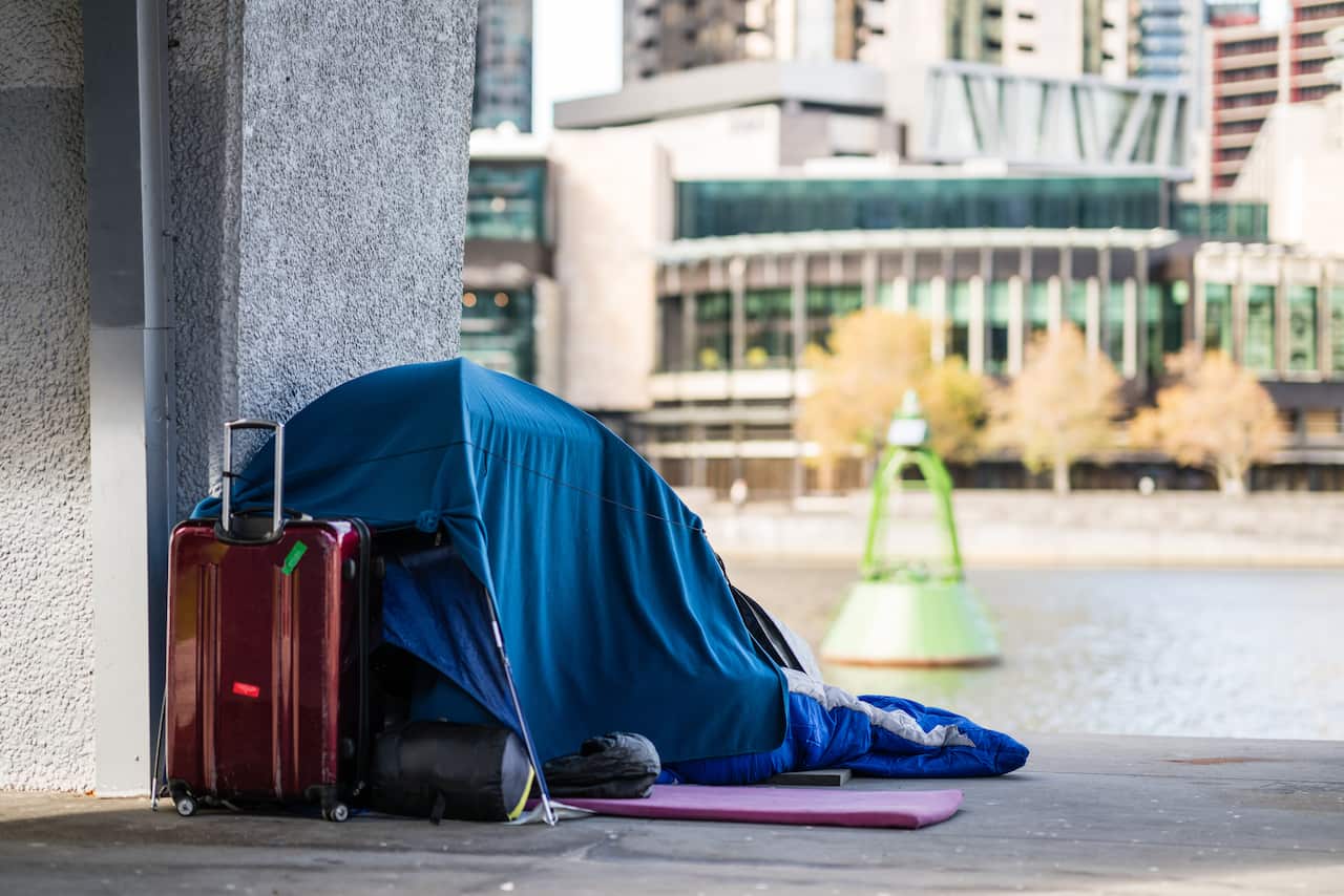 A tent with a suitcase next to it in the city.
