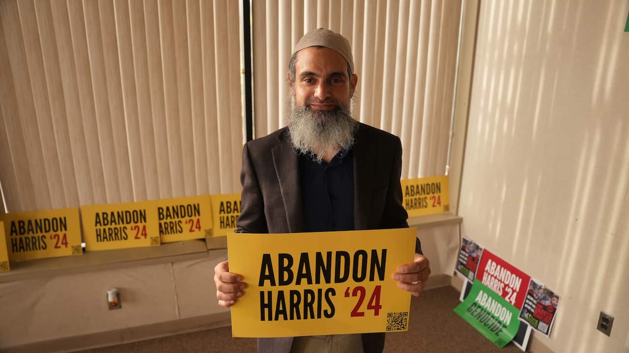 A man holding a sign reading 'abandon Harris'