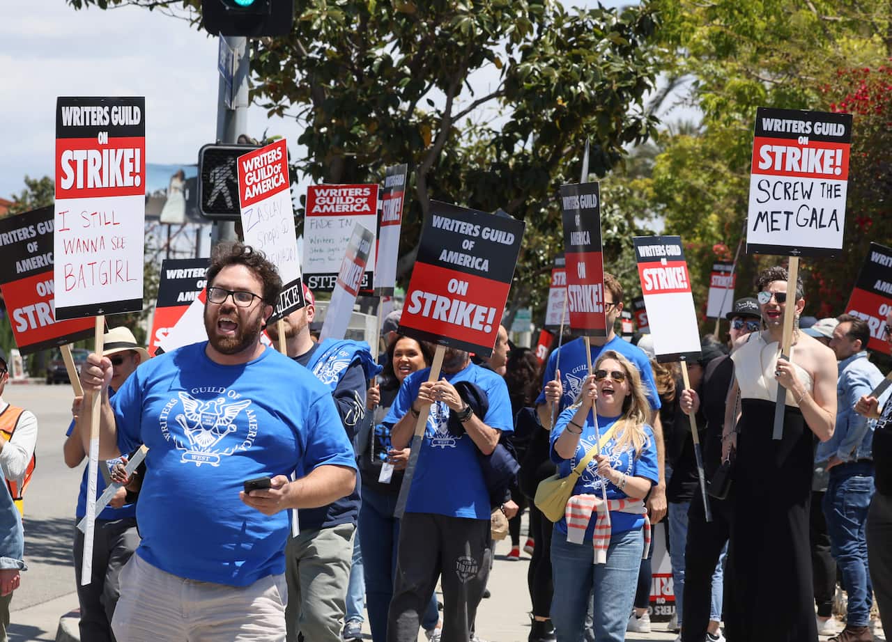 A group of people hold up placards reading "Writers Guild on strike"