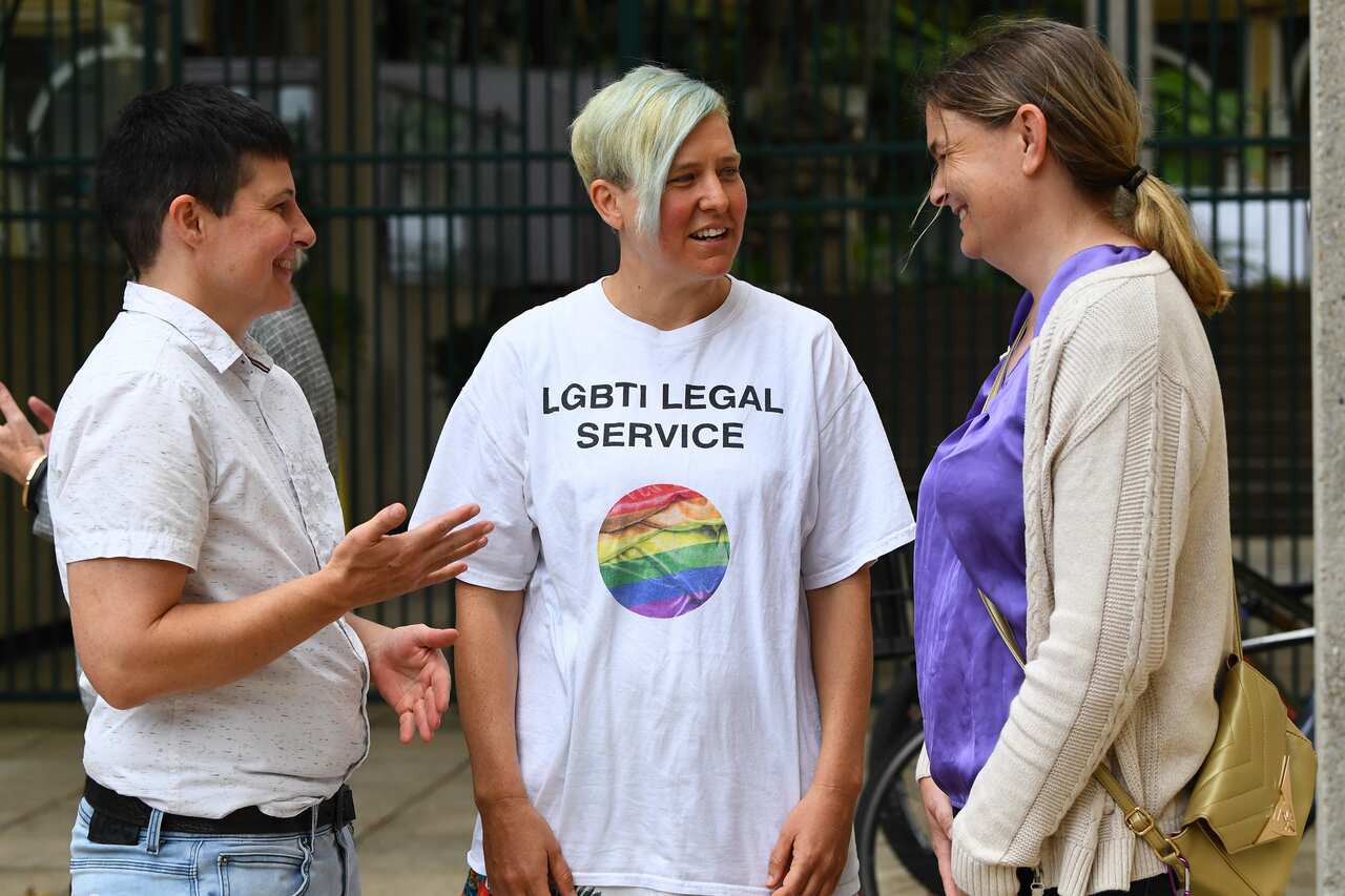 Three people stand next to one another and chat.