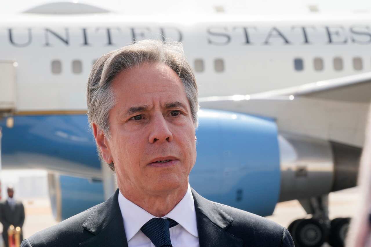 Antony Blinken standing in front of an aircraft that says 'United States'.