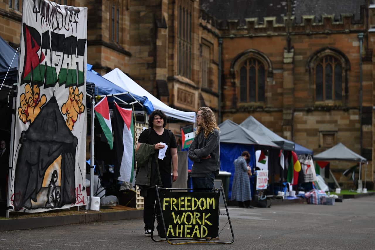 Tents set up outside a sandstone building on a university campus.