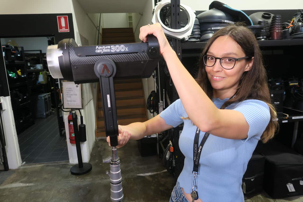 Woman looking at camera holding a professional light 
