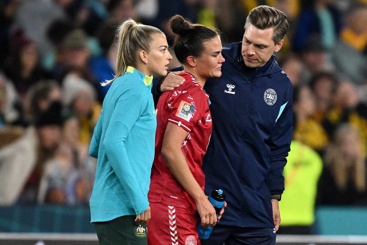 A football players in red jersey is consoled by teammates after a loss.