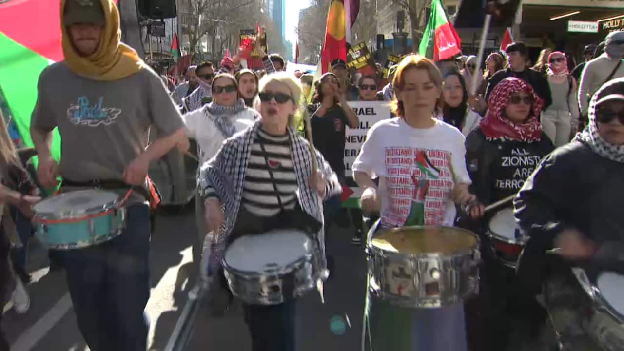 A group of people drumming at the front of a protest march.