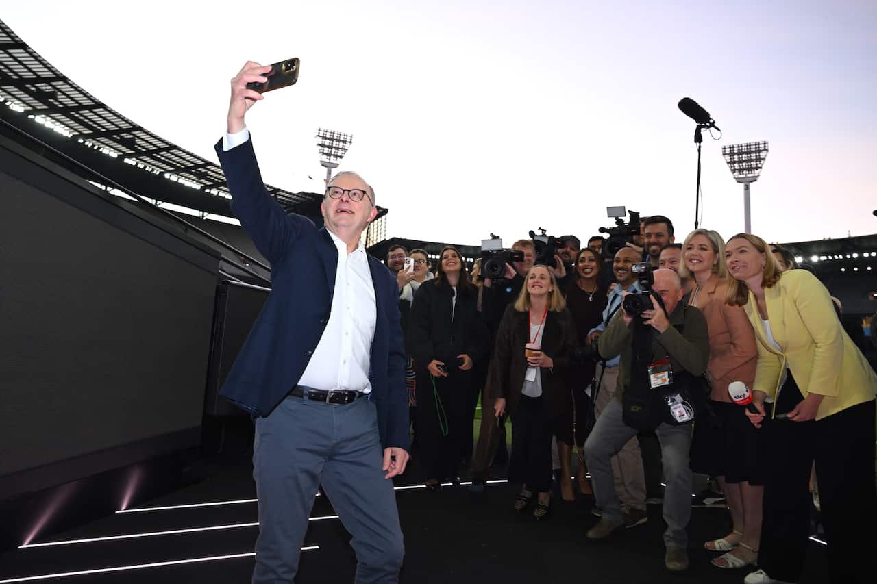 Anthony Albanese takes a selfie in front of a large group of people.