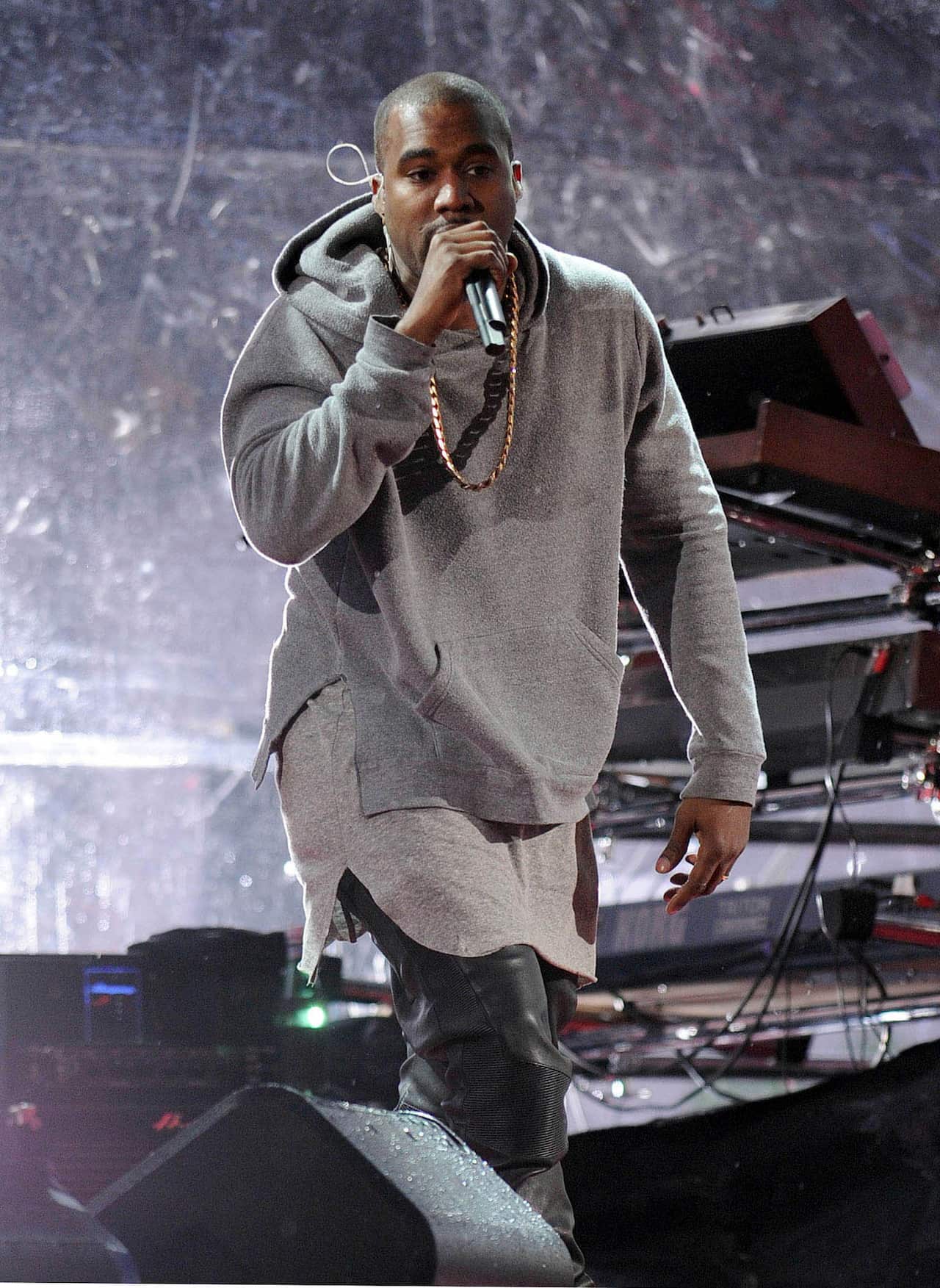 A musician wearing a grey hoodie is singing into the microphone.
