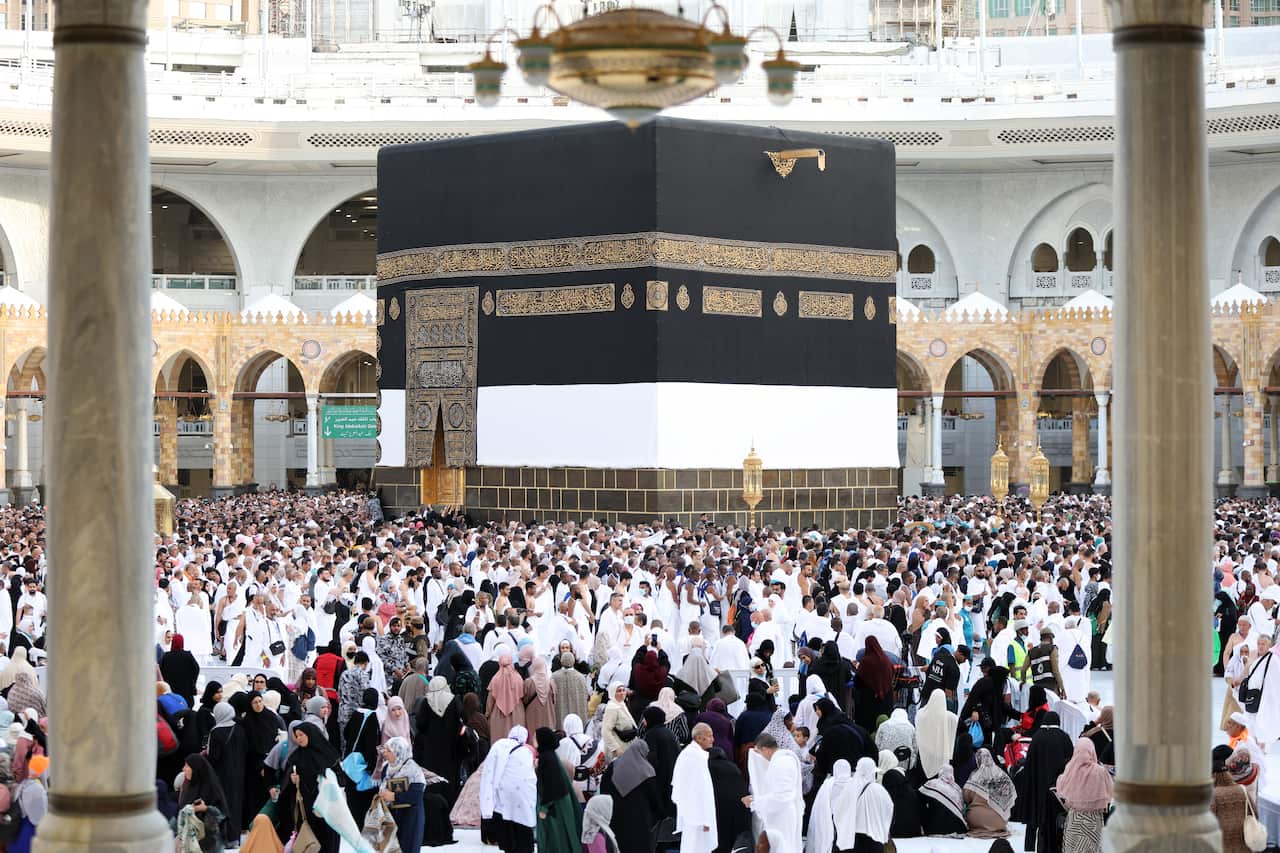 A large group of people circling a large cubic shrine.
