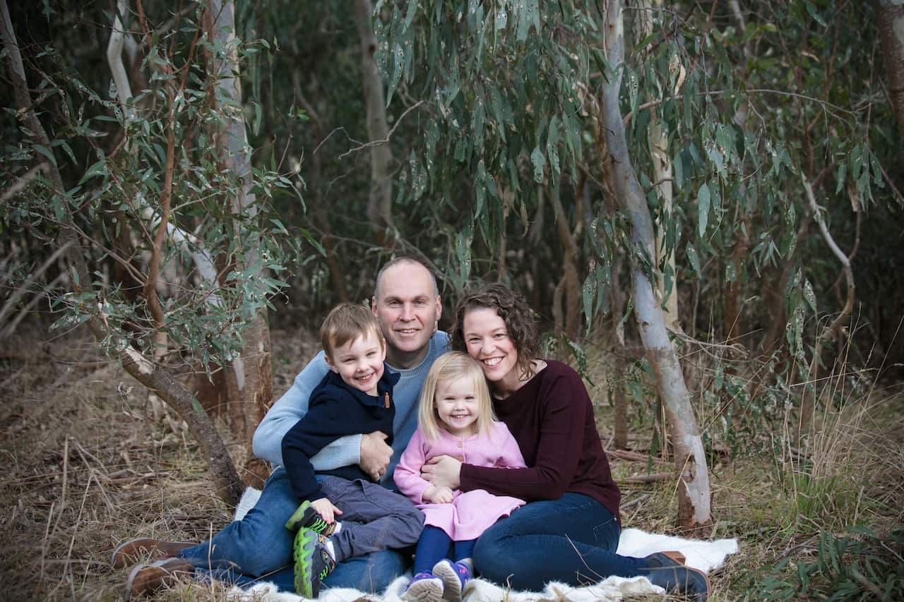 Pip Reid with husband and young chidren sitting in nature for a family photo