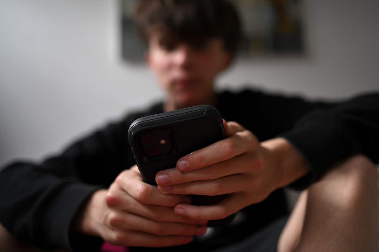A teenager uses his mobile phone to access social media