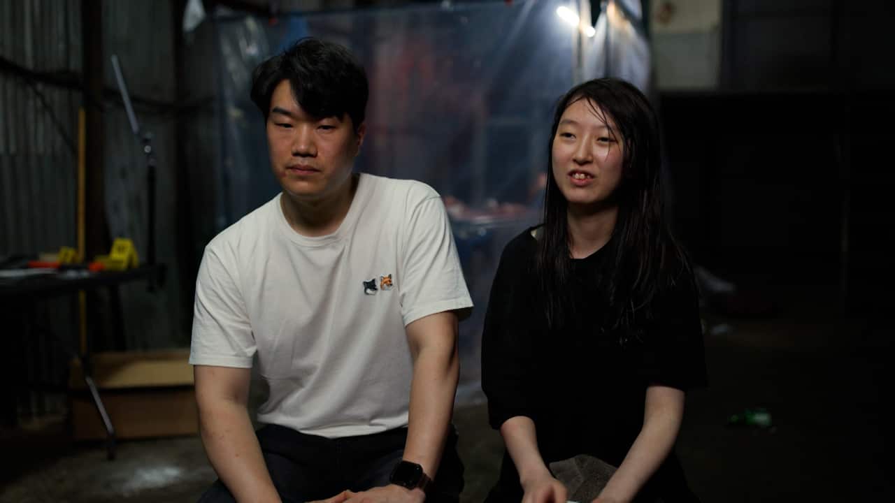 A young man and woman sit together while being interviewed for a film.