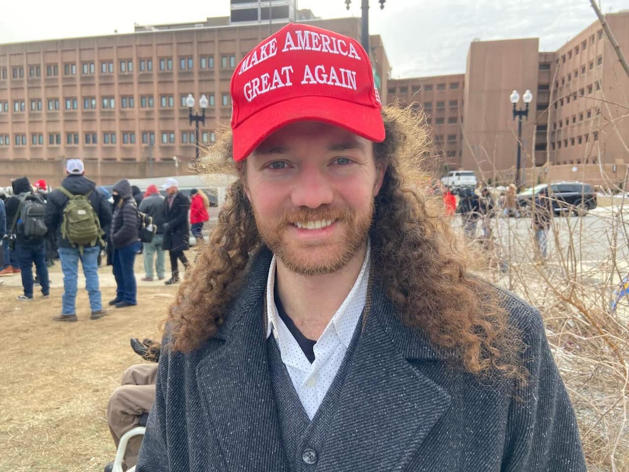 A man with long hair wearing a 'MAKE AMERICA GREAT AGAIN' hat.