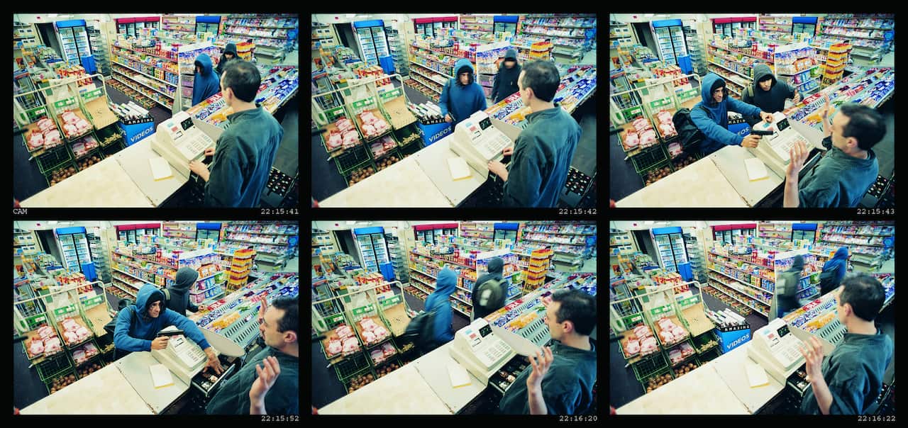 High Angle View of Two Robbers Robbing a Cash Till and Threatening a Shop Assistant with a Gun