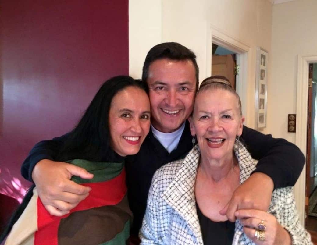 (left to right) Marina Tamayo, her brother and her mother standing inside. Her brother has his arms around both women. 