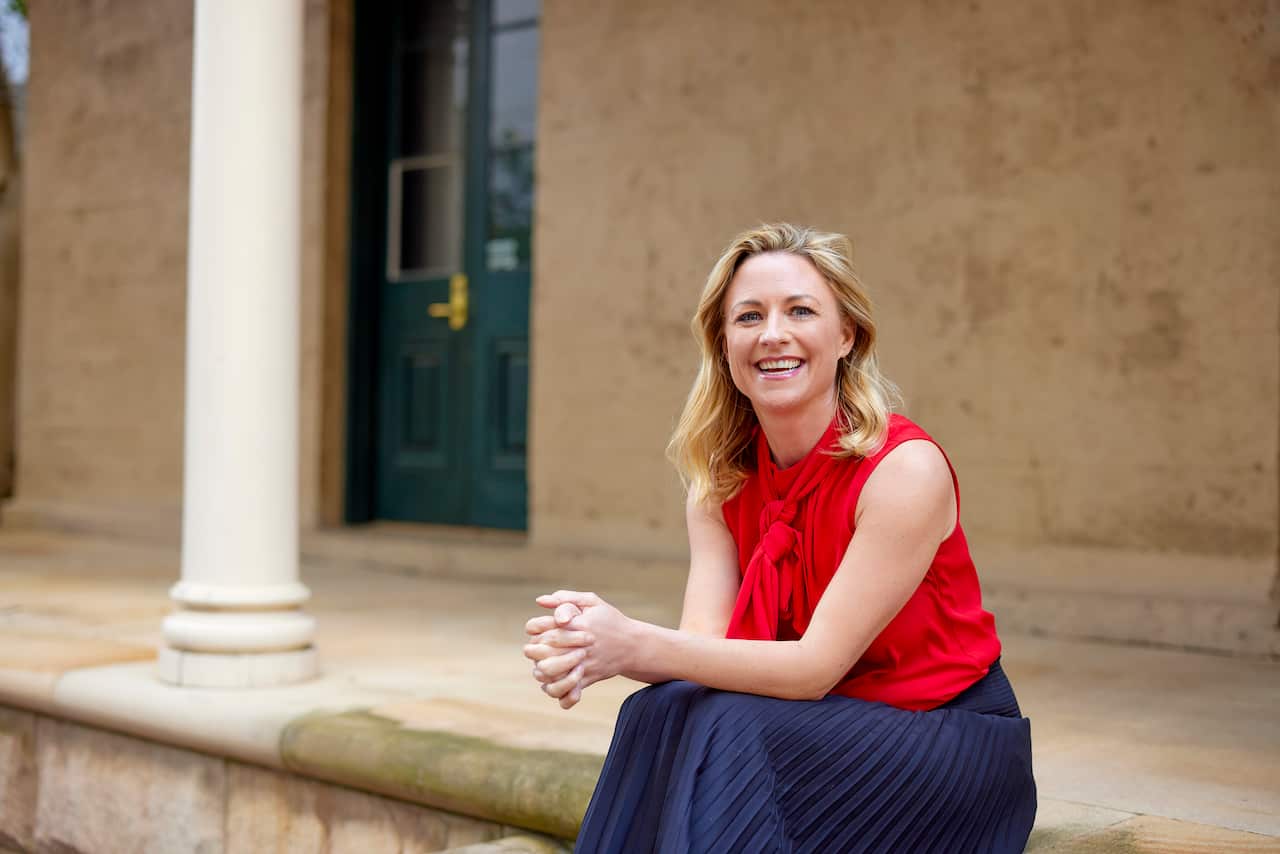 Sally Tindall sitting on a step with her hands together in front of her.