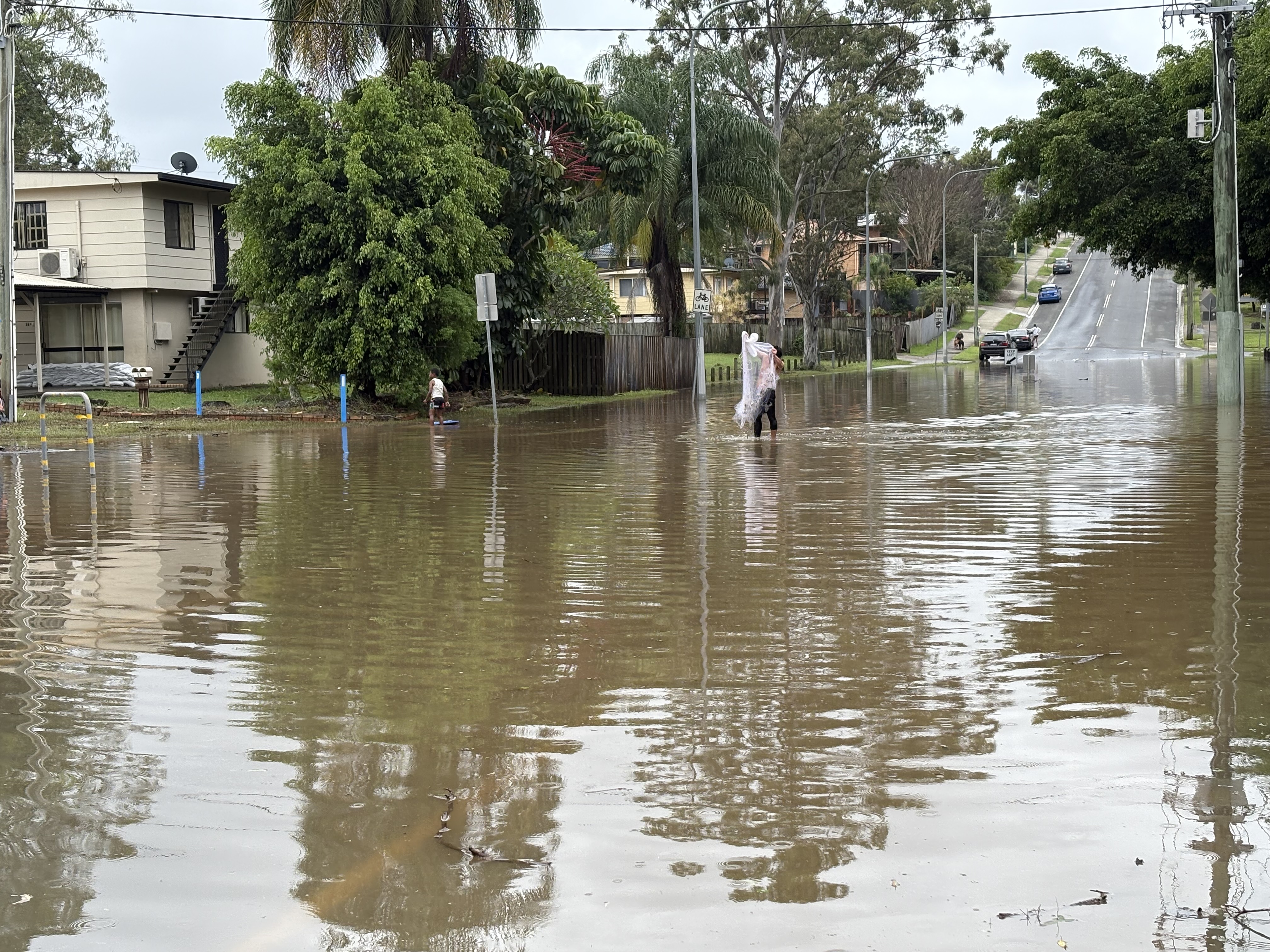 A person crosses a flooded road.
