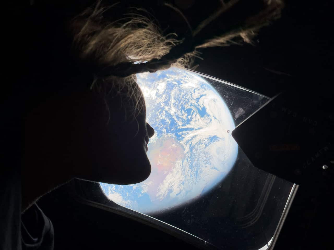 A view of Earth from space with an astronaut looking out the spaceship's window
