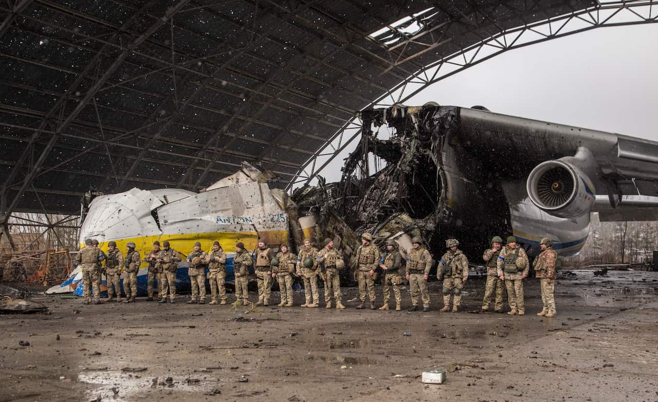 Ukrainian servicemen standing in front of a destroyed Russian aeroplane.