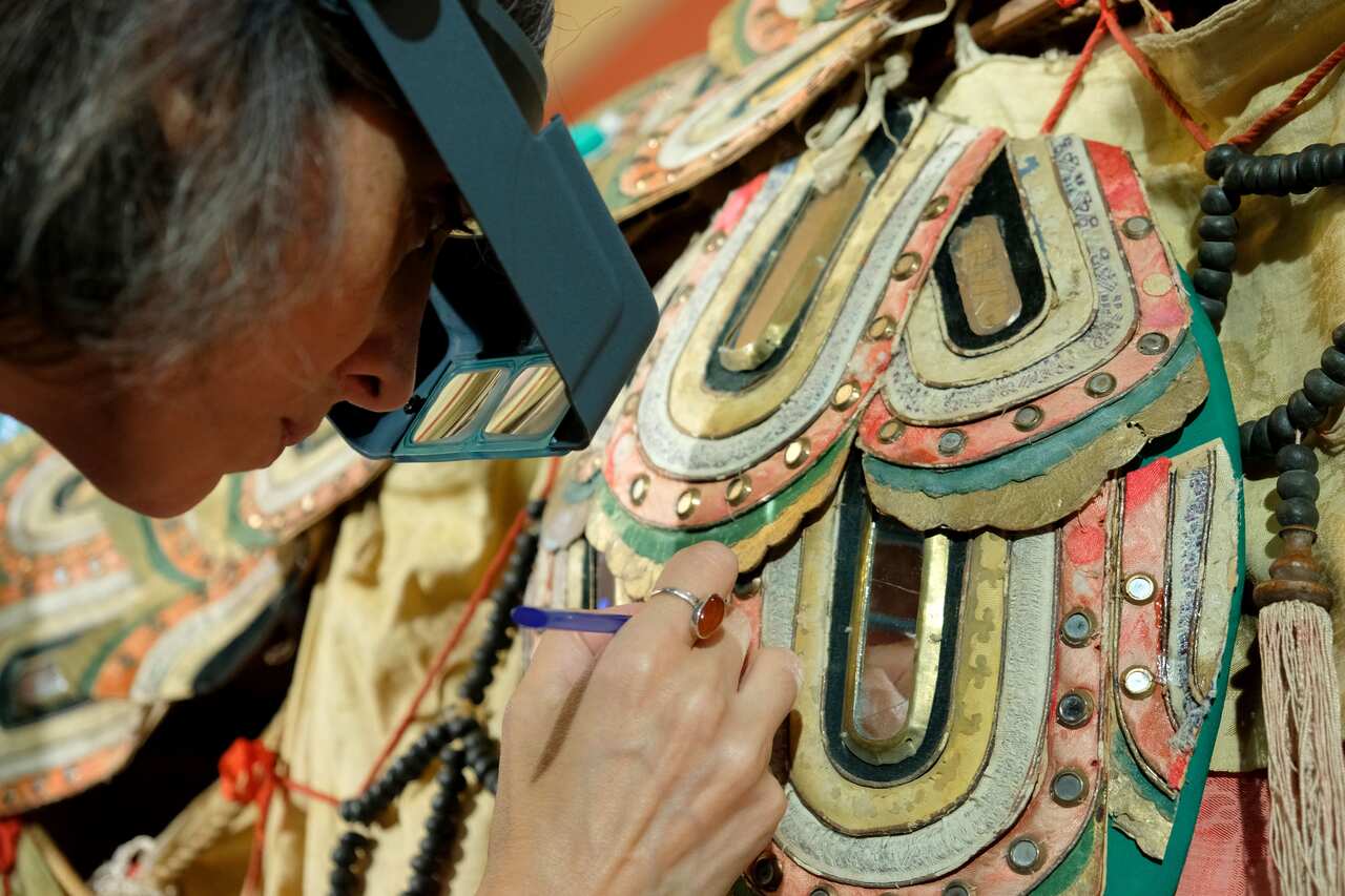 A woman holds an implement as part of restoration work of fabric squares