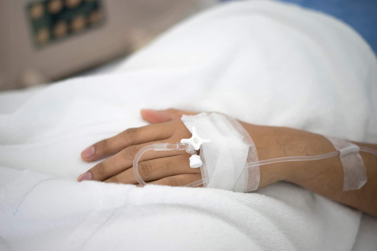 A person's hand with an IV drip attached.