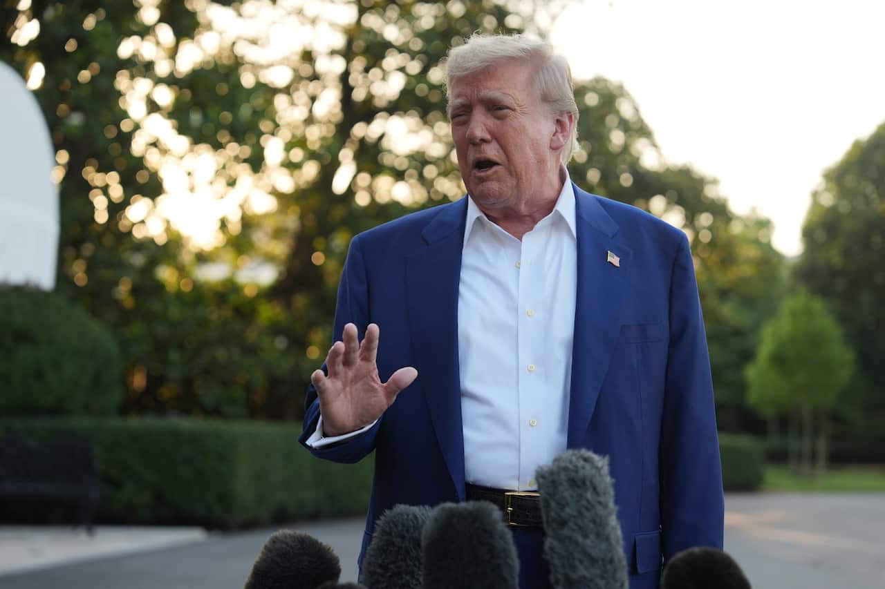 Donald Trump in a blue blazer and white shirt, speaking in front of a lawn.